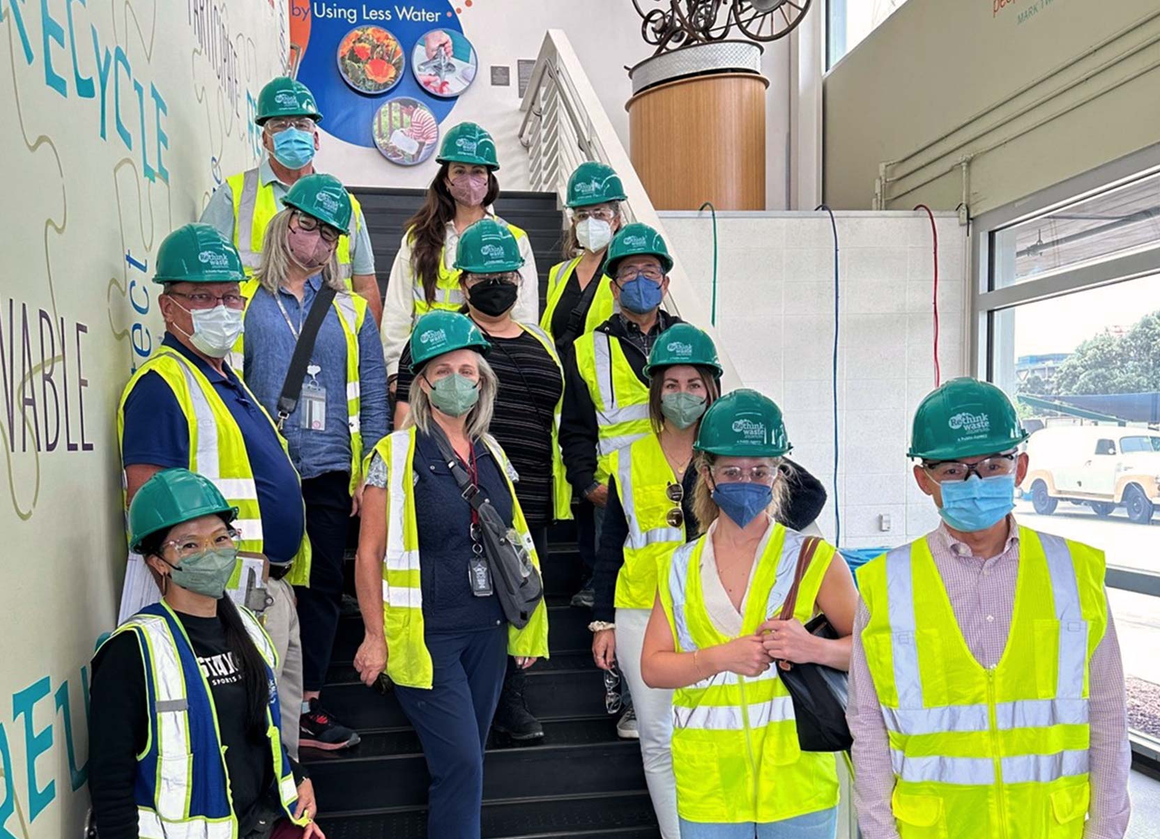 Group wearing high visibility jackets and safety helmets on a Recology Tour at Stanford Redwoods campus.