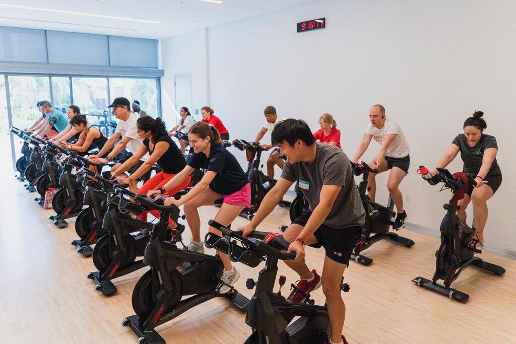 A row of people participate in an indoor cycling class during the Cardinal Tri event.